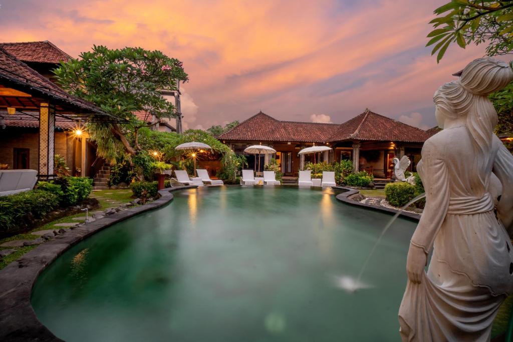 a pool at a resort with a statue in the foreground at Capung Cottages in Ubud