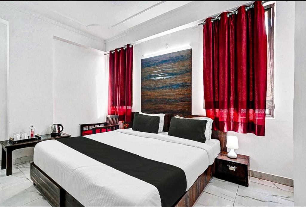 1 dormitorio con 1 cama grande y cortinas rojas en COLLECTION O HOTEL SKY INN en Jaipur