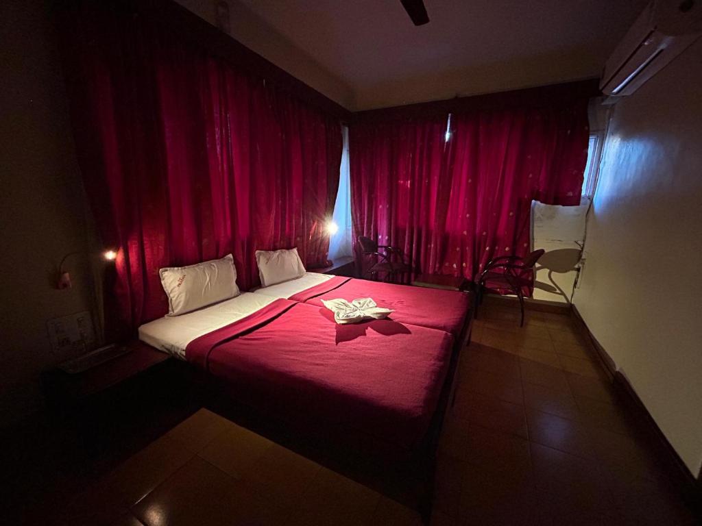 a bedroom with red curtains and a bed with a red blanket at Hotel Prabha in Ratnagiri