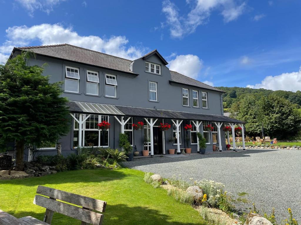 uma grande casa cinzenta com flores vermelhas em frente em Elan Valley Hotel em Rhayader