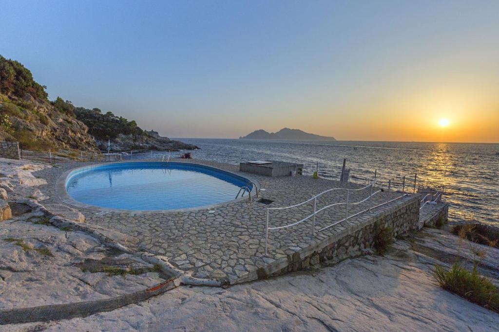 a swimming pool on the beach at sunset at AMORE RENTALS - Villa Domus Franca in Massa Lubrense
