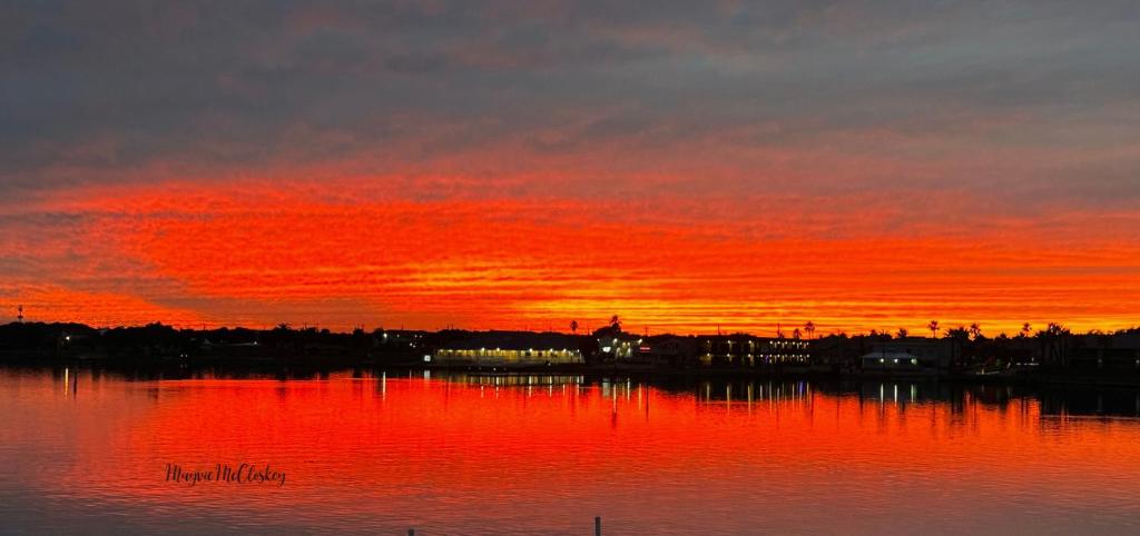 una puesta de sol sobre un cuerpo de agua con un cielo rojo en Waterfront Guesthouse on Key Allegro/Little Bay with dock en Rockport