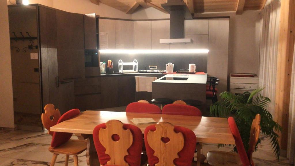 una cucina con tavolo in legno e sedie rosse di Villa Claudia a Livigno