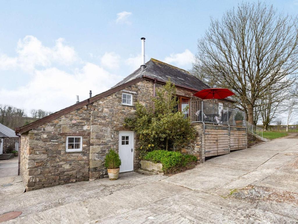 a stone house with a red umbrella in front of it at 3 Bed in Launceston 36820 in Linkinhorne