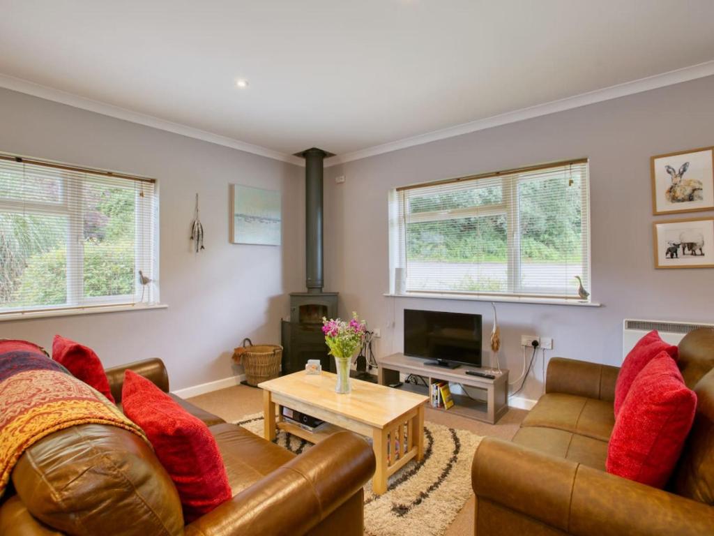 a living room with two couches and a table at Fernhill Cottage, Jurassic Coast in Charmouth