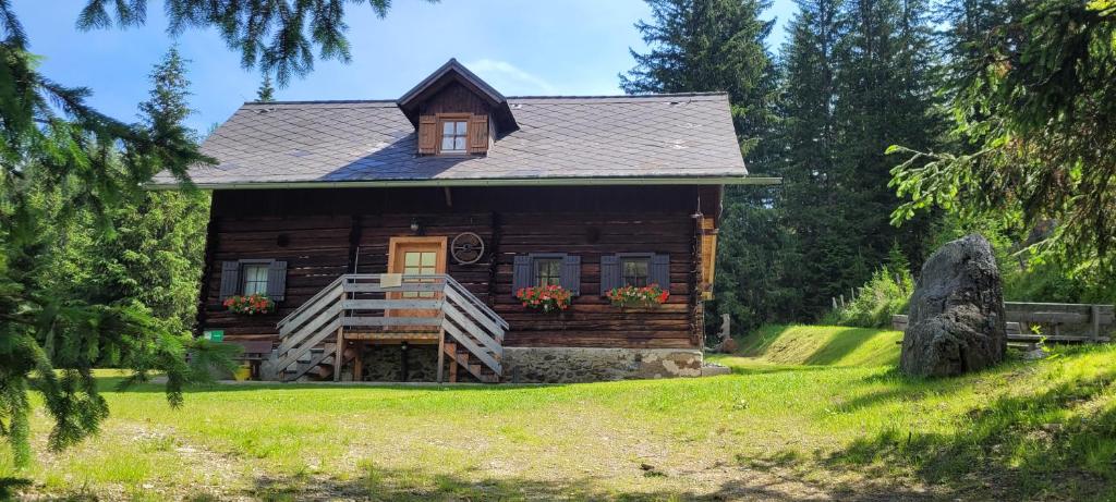 une cabane en rondins au milieu d'un champ dans l'établissement Fuggerhütte, à Flattnitz