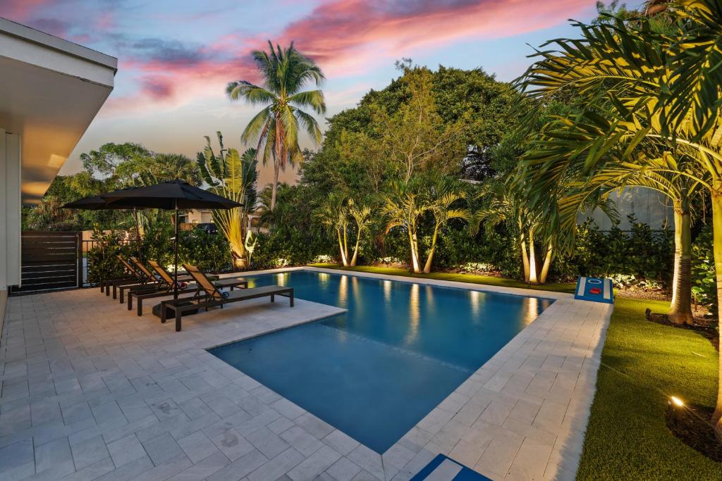 basen w ogrodzie z ławkami i drzewami w obiekcie Paradise Palms House w mieście Delray Beach
