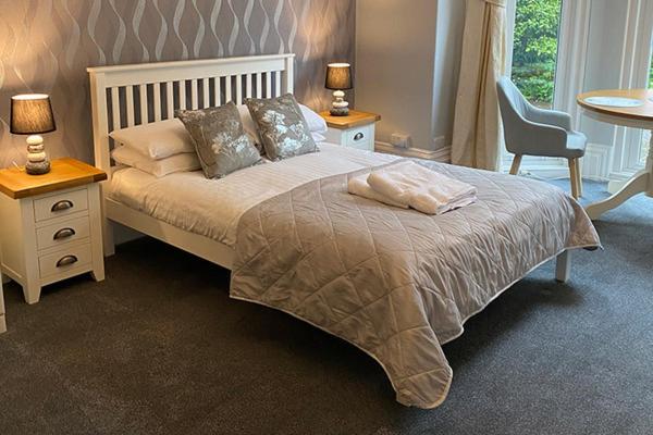 1 dormitorio con 1 cama con 2 mesas y 1 silla en Barramore Holiday Apartments en Torquay