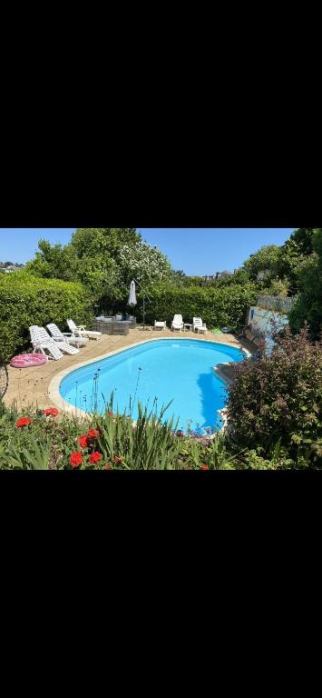 a large swimming pool with chairs and flowers at Barramore Holiday Apartments in Torquay