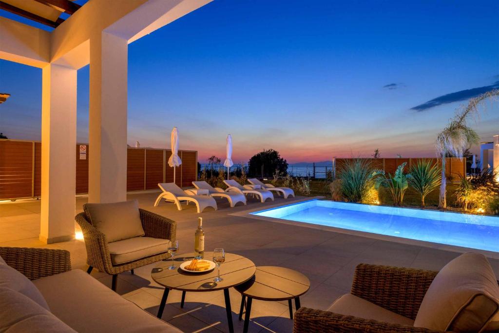 a patio with chairs and a pool at night at Villa Panaxia Kohille in Theologos