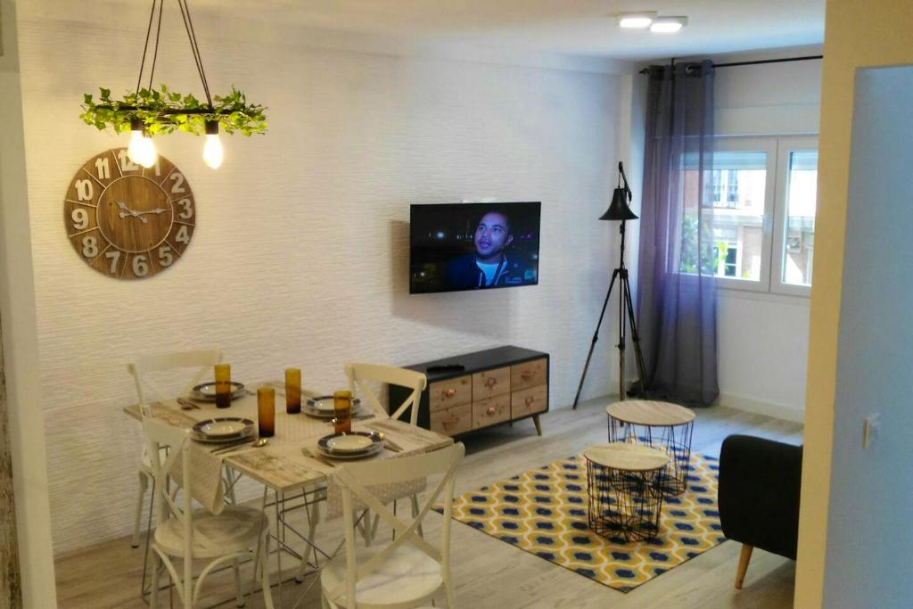 sala de estar con mesa y TV en la pared en 2 bedrooms appartement at Gijon, en Oviedo