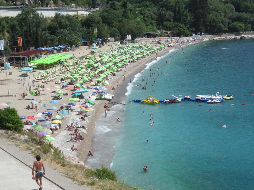 a group of people on a beach with umbrellas at Apartments Danilo Kažanegra in Sveti Stefan