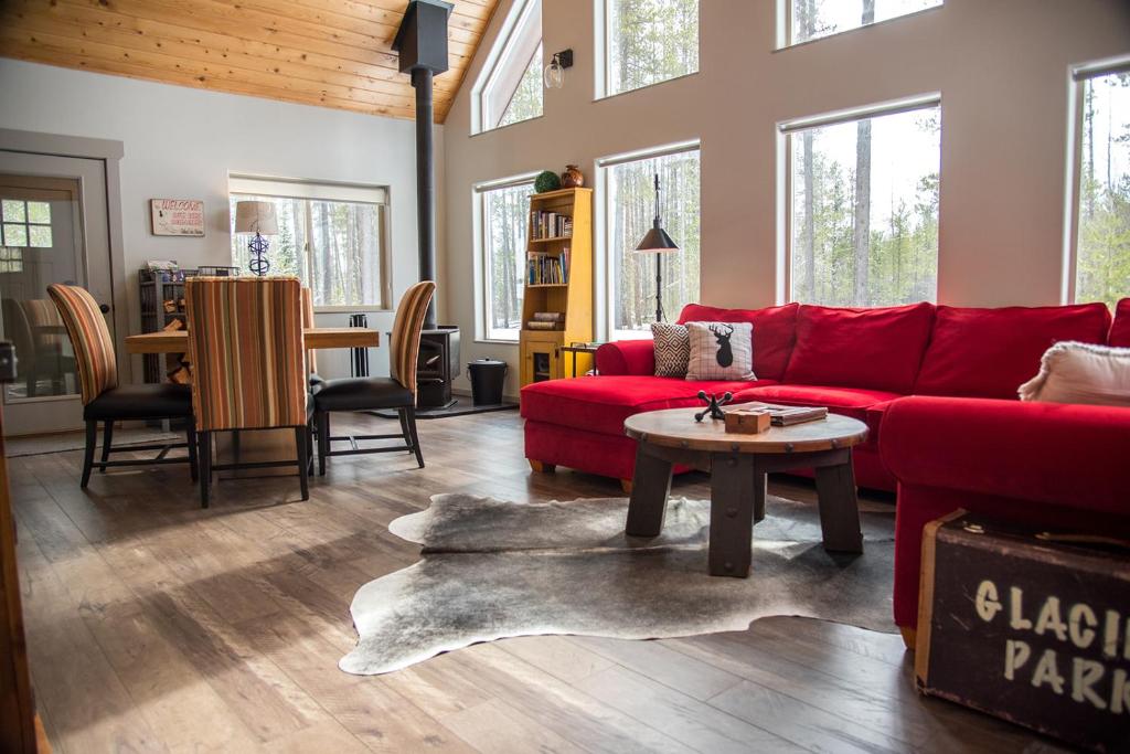 a living room with a red couch and a table at Elk Street Retreat - Near Glacier Park in Columbia Falls