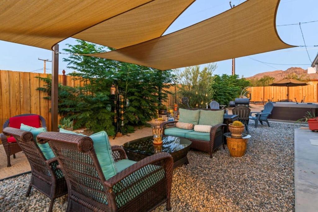 a patio with chairs and a couch under a large umbrella at Haven Rock- Secluded Oasis and Sanctuary Gardens in Joshua Tree