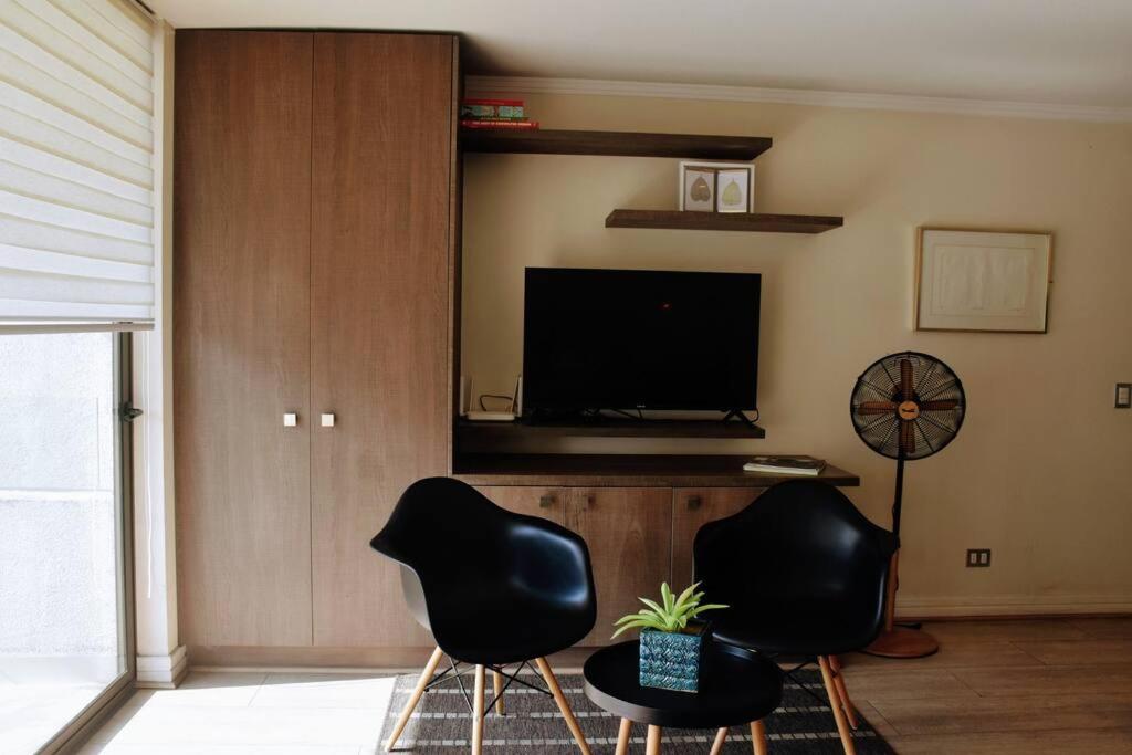 a living room with two chairs and a flat screen tv at Arauco Apartment in Santiago