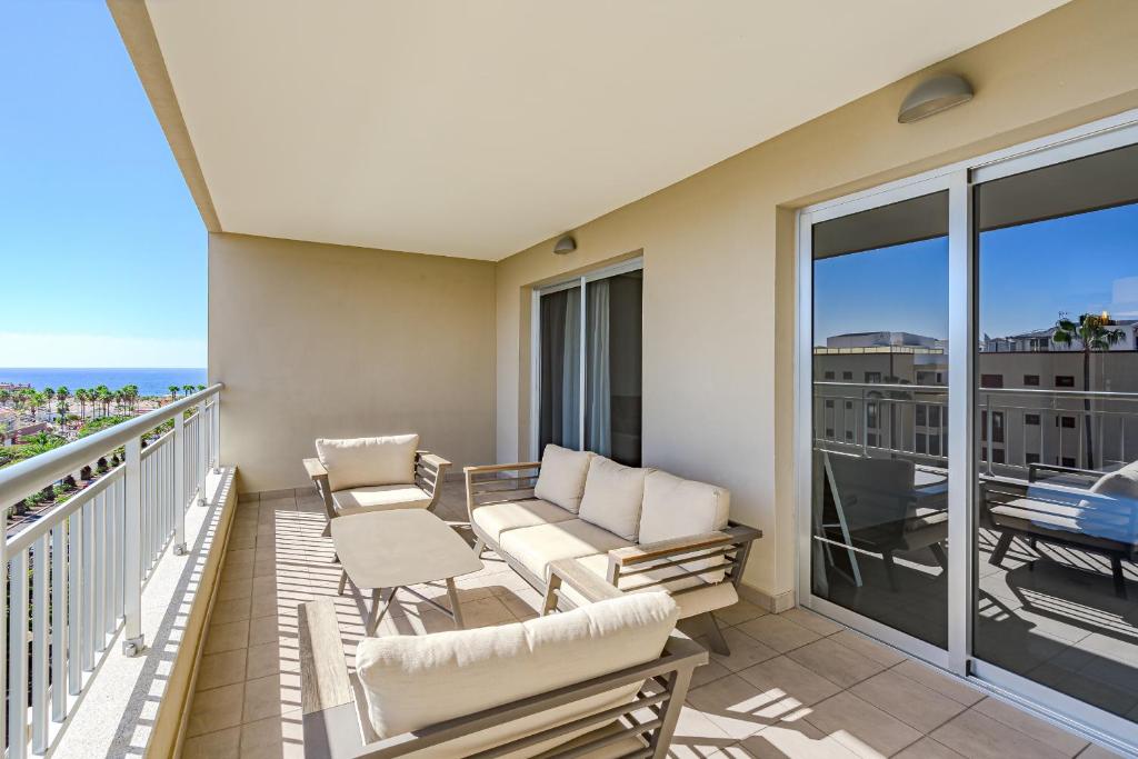 einen Balkon mit Sofa und Stühlen darauf in der Unterkunft Calm Palmar By W Tenerife in Palm-mar