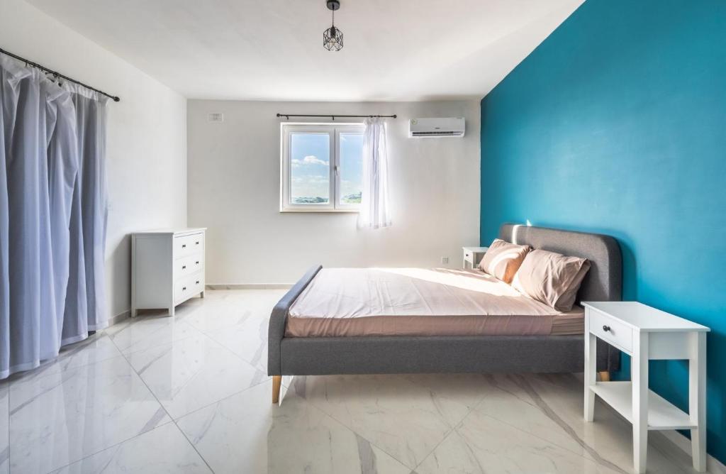 1 dormitorio con cama y pared azul en Sunset Bliss Luxury Apartment en St Paul's Bay