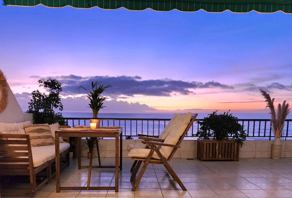 a balcony with a table and chairs and a view of the ocean at Ocean Wave in Acantilado de los Gigantes