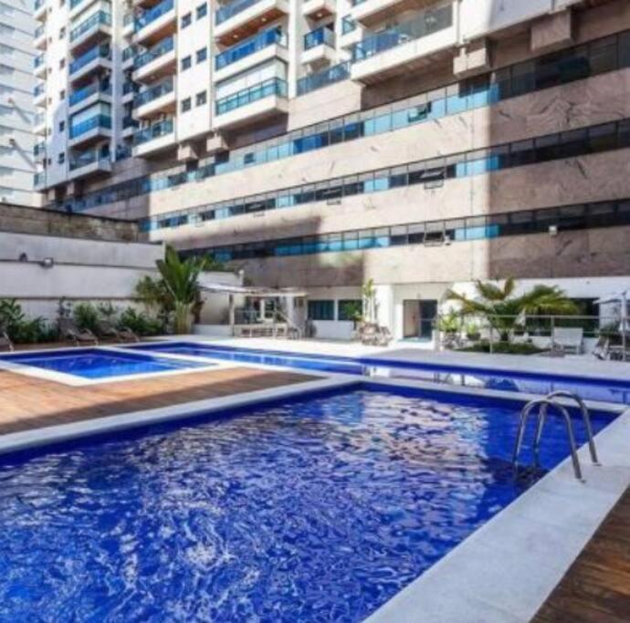 a large swimming pool in front of a building at Novo Flat Capitania Varan in Guarujá