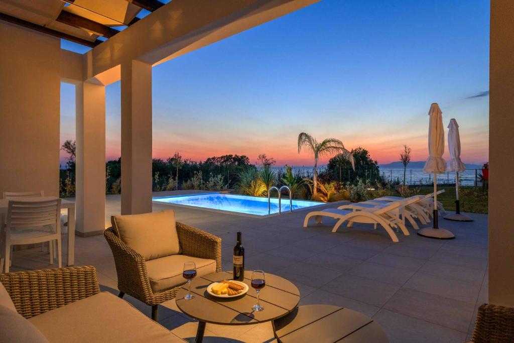a patio with a table and chairs and a pool at Villa Panaxia Votsalo in Theologos