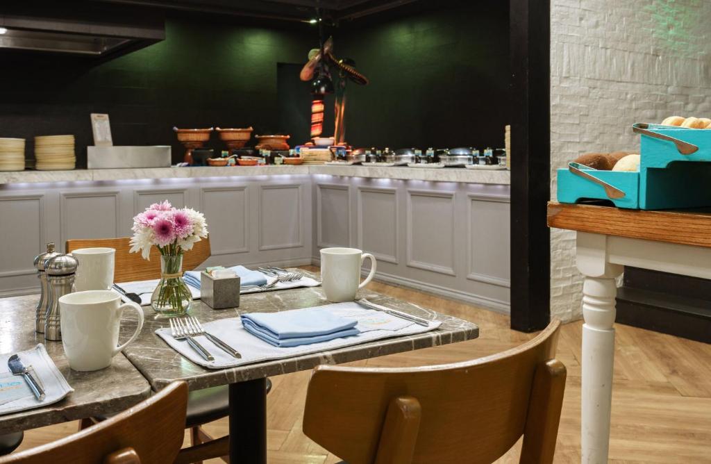 A breakfast dining area beside a buffet counter with coffee service and pastries.