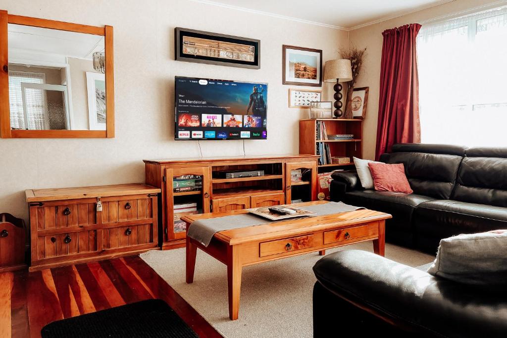 ein Wohnzimmer mit einem Sofa und einem Tisch in der Unterkunft Alpine House Tongariro - Turangi Holiday Home in Turangi