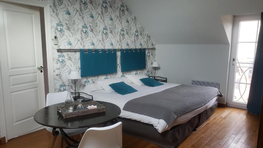 a bedroom with a large bed and a table at La Closerie des Sacres in Lavannes