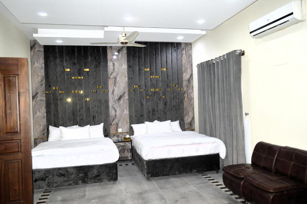 a bedroom with two beds and a couch at Rose Valet Guest House in Islamabad