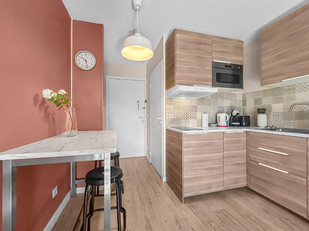 a kitchen with a counter and a clock on the wall at Studio Lumineux au Cœur de Toulouse in Toulouse