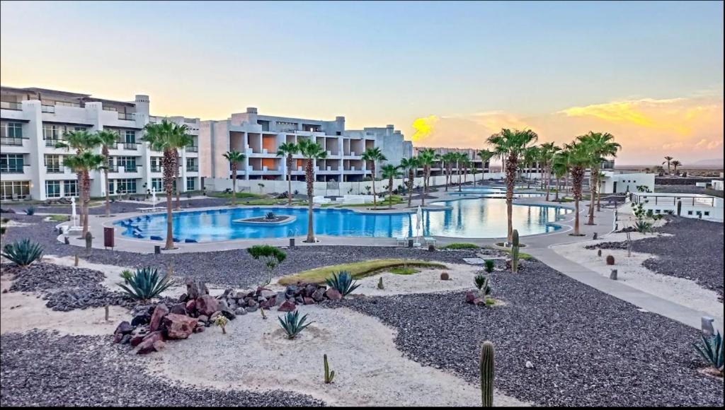 een resort met een zwembad met palmbomen en een gebouw bij Casa Wixson At Mayan Lakes 3-304 in Playa Encanto