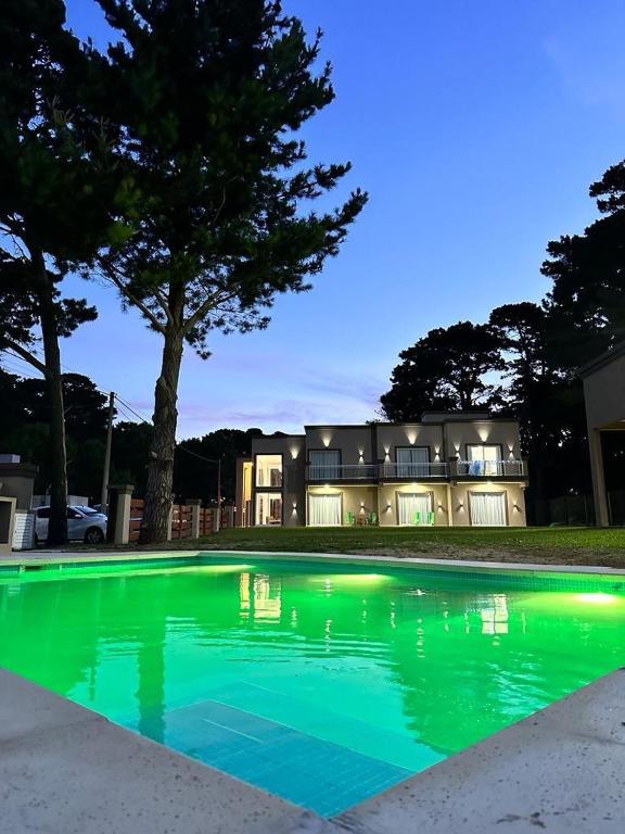 a large green pool with a house in the background at La mansa del pinar in La Lucila del Mar