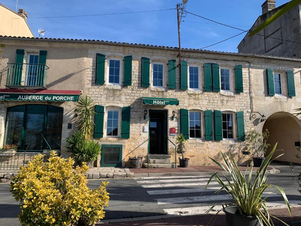 a stone building with green shutters on a street at AUBERGE DU PORCHE in Blaye