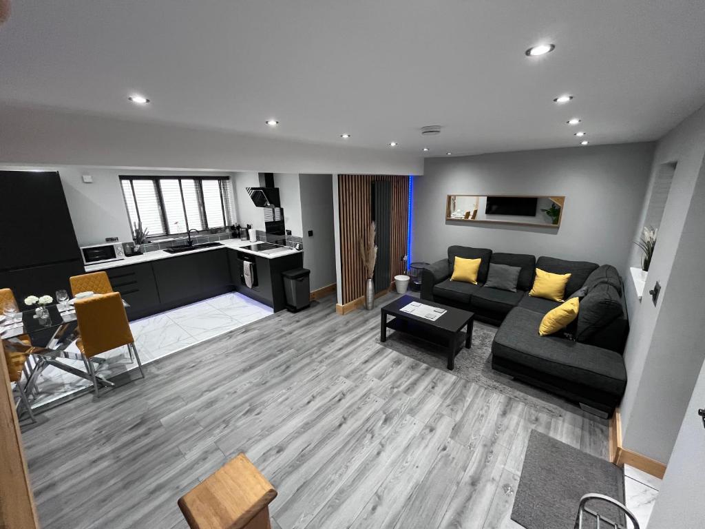 a living room with a black couch and a kitchen at Entire Two Bedroom Guest House & Free Parking in Nottingham
