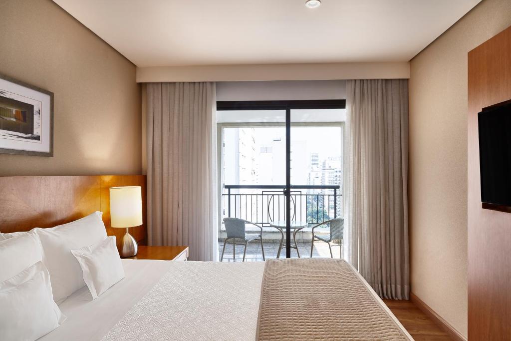 a hotel room with a bed and a balcony at George V Casa Branca in São Paulo