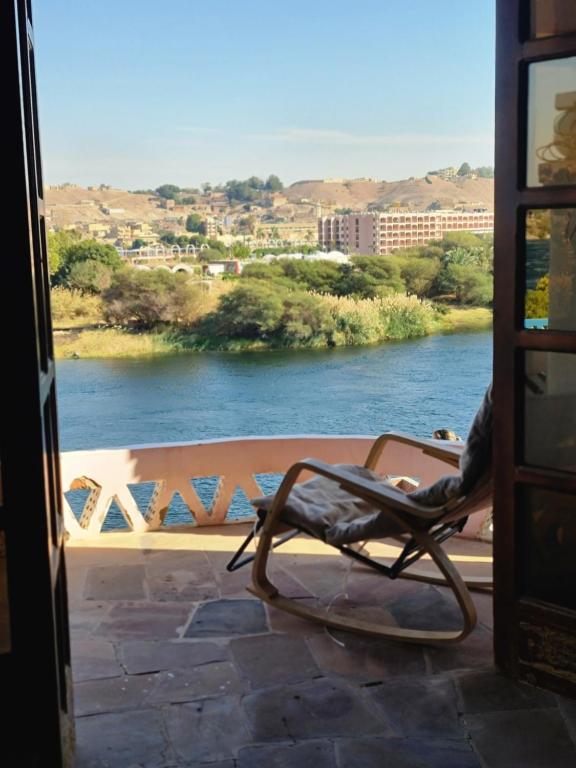 a chair on a porch with a view of a river at Nubian Magic villa in Nag` el-Ramla