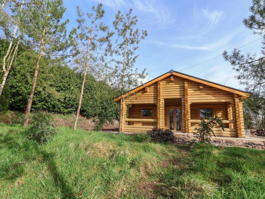 a log cabin in the woods with a field at Redwood Lodge in Ellesmere