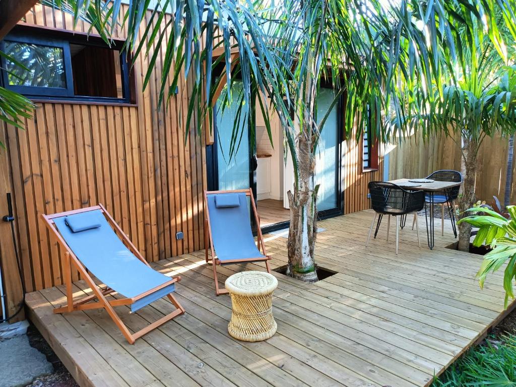 2 chaises et une table sur une terrasse en bois dans l'établissement Tiny house au lagon, à Saint-Paul