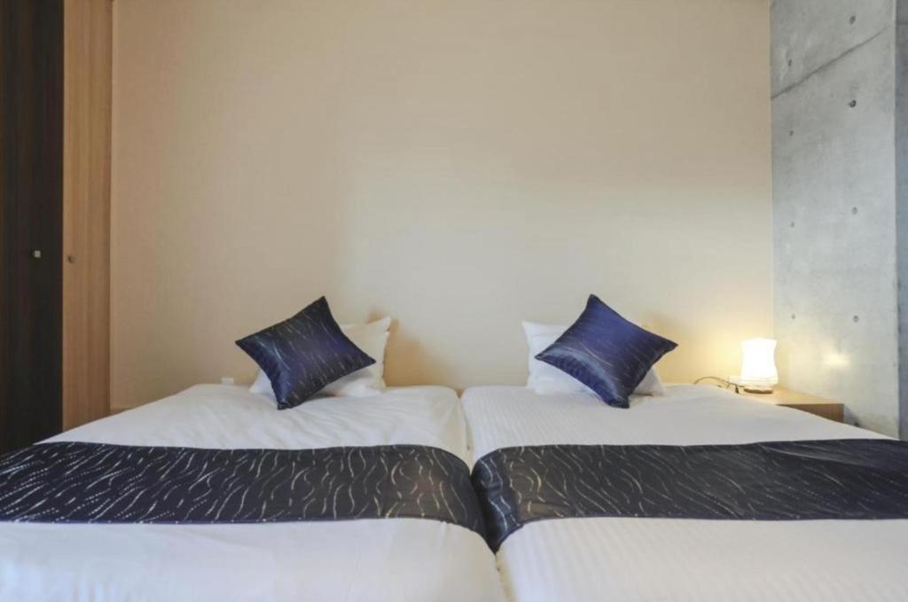 2 łóżka w pokoju hotelowym z niebieskimi poduszkami w obiekcie Nagano family - Vacation STAY 58421v w mieście Kioto