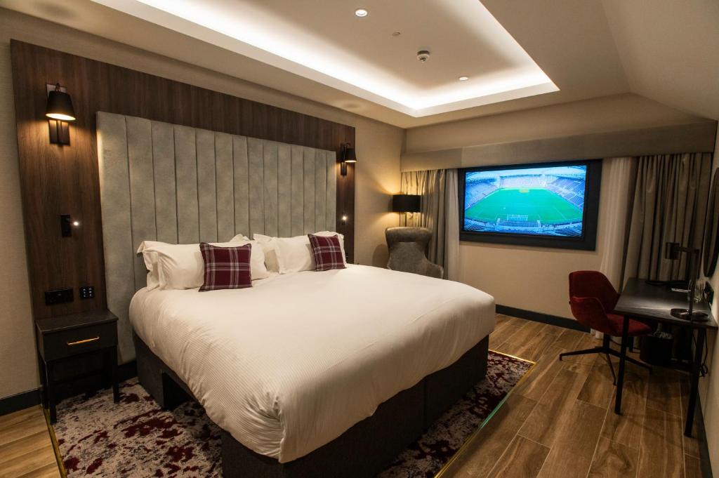 um quarto com uma cama grande e uma televisão em Tynecastle Park Hotel em Edinburgo