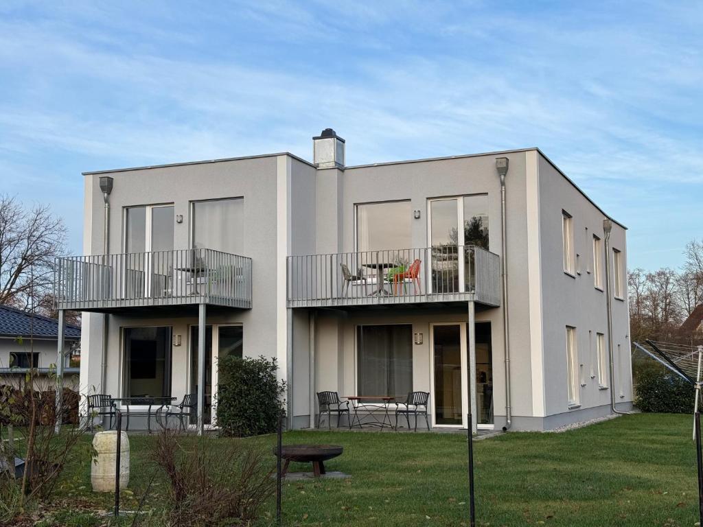 ein weißes Haus mit zwei Balkonen und einem Hof in der Unterkunft Haus Am Anger in Hangelsberg