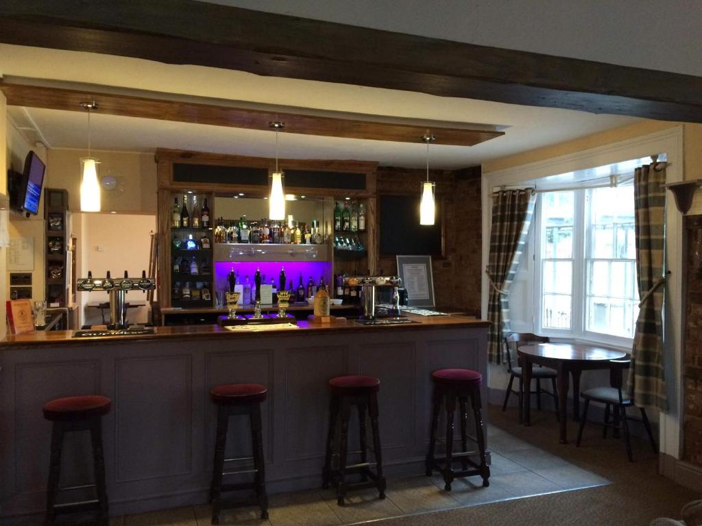 a bar with red stools in a room at The Chase Inn in Bishops Frome