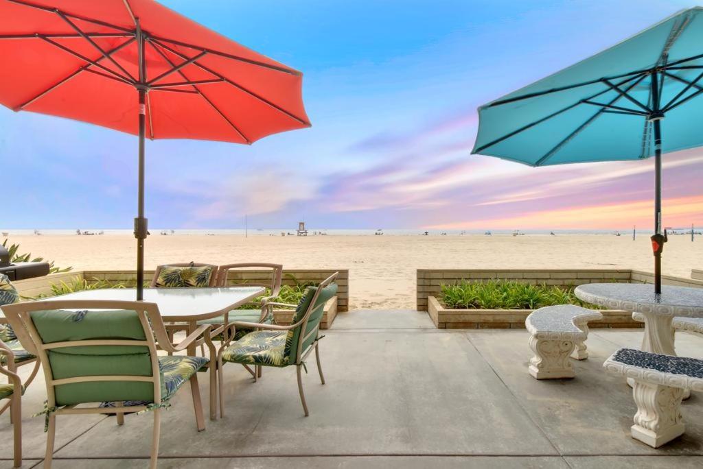 um pátio com mesas e guarda-sóis na praia em West Newport Duplex on the Sand with Patio-Sleeps 12 em Newport Beach