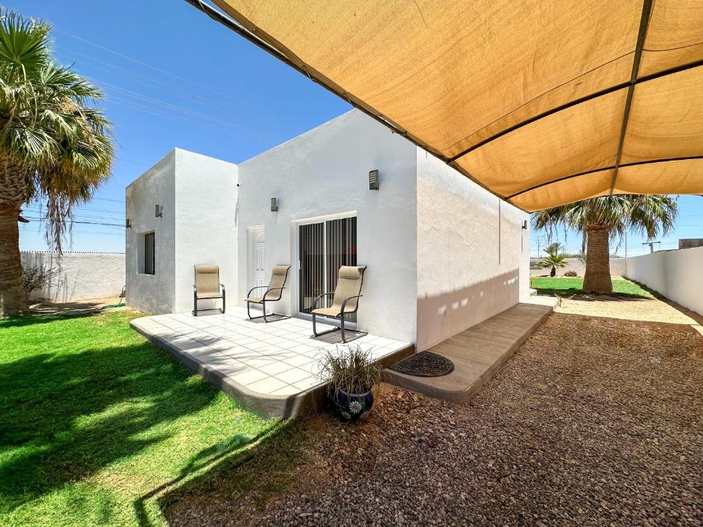 a white house with two chairs on a patio at Embrace Serenity in a Cozy 2-Bedroom House in Puerto Peñasco