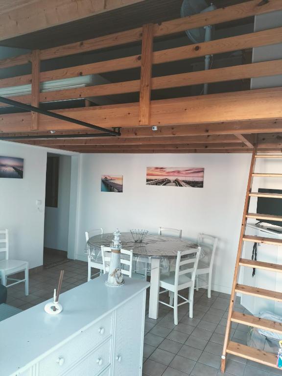 une salle à manger avec une table et une échelle dans l'établissement Maison calme proche mer - La Roseraie, à Saint-Hilaire-de-Riez