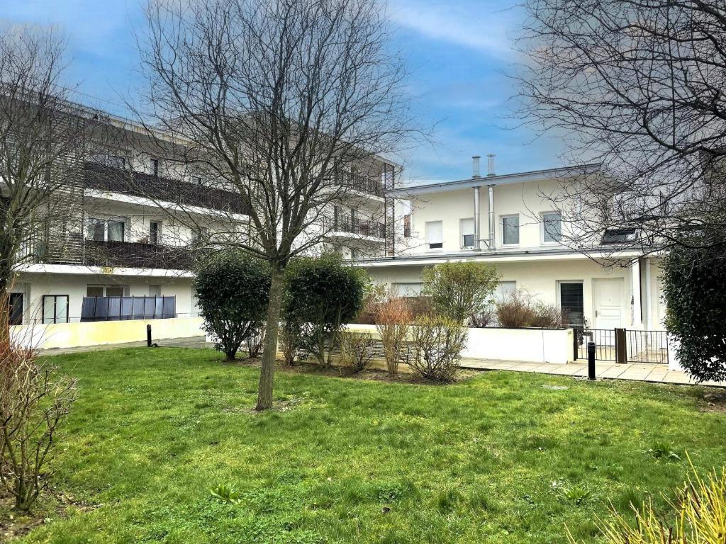 a tree in a yard in front of a building at Appartement spacieux avec rooftop et garages privés à 3 min de la gare d'Épernon - FR-1-581-129 in Épernon