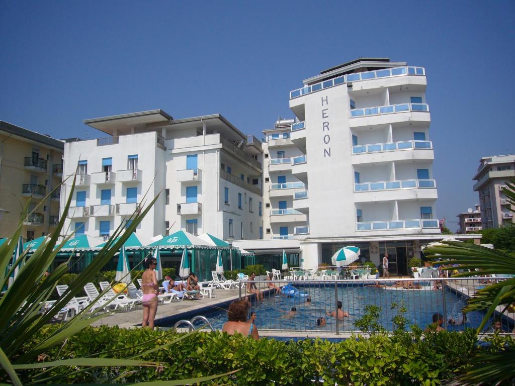 un hotel con piscina di fronte a un edificio di Hotel Heron a Lido di Jesolo