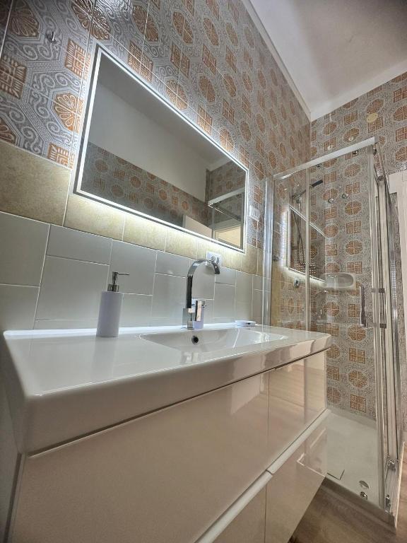 a white bathroom with a sink and a mirror at ATTICO MANFREDI in Foggia