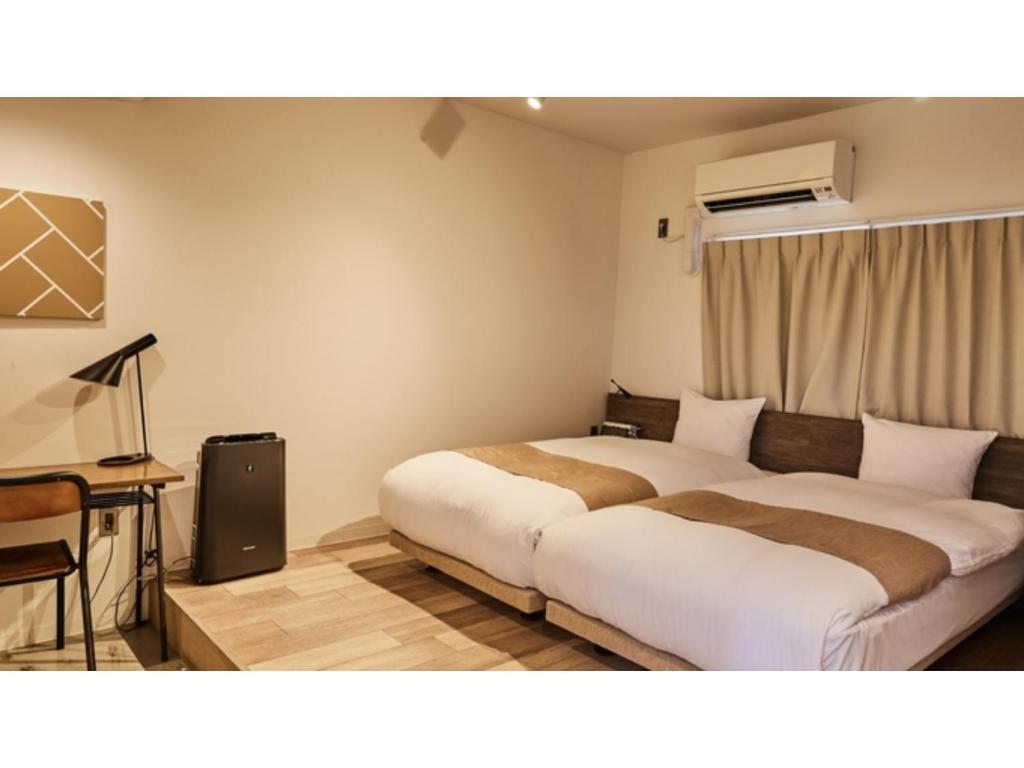 a hotel room with two beds and a table and a desk at River Side Arashiyama - Vacation STAY 86031v in Kyoto
