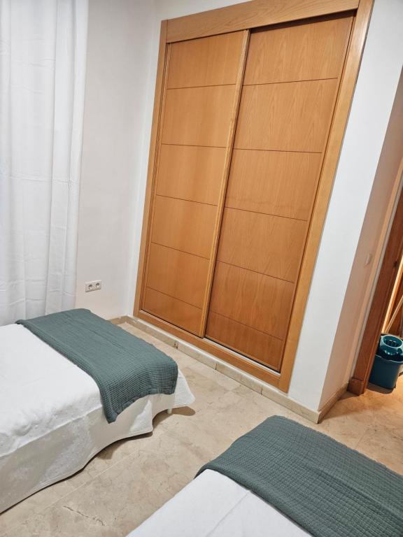 1 dormitorio con cama y armario de madera en Arenal golf Sun & golf, en Benalmádena