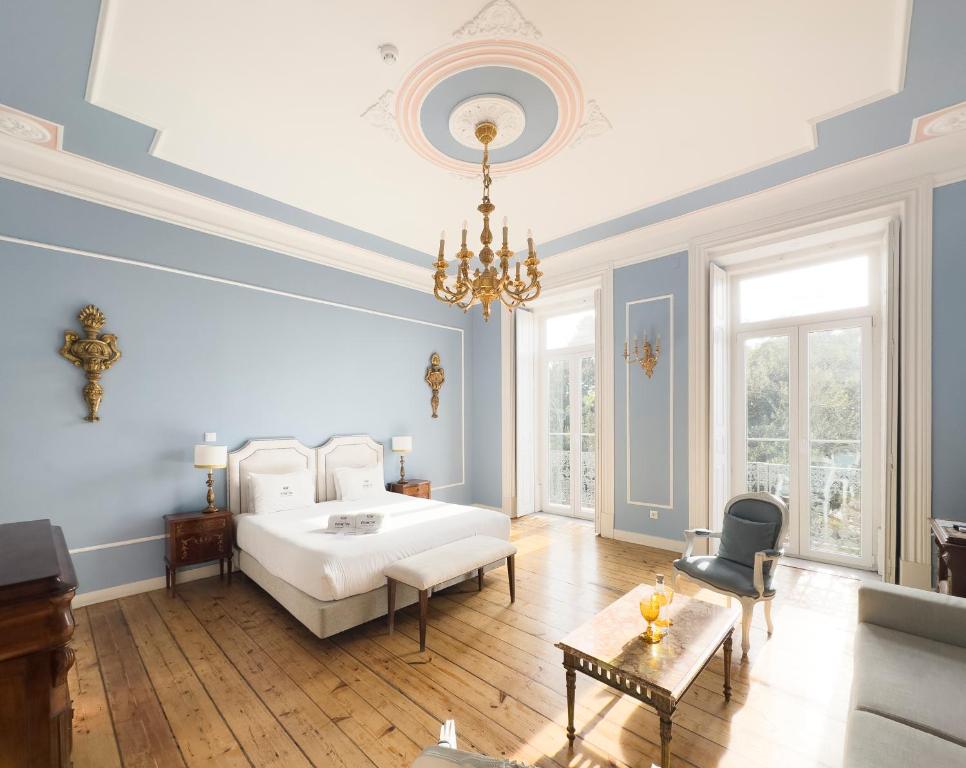 a bedroom with a white bed and a chandelier at Casa do Principe in Lisbon